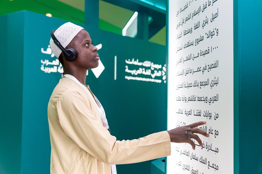 شاب يشير إلى جدارية مكتوبة باللغة العربية